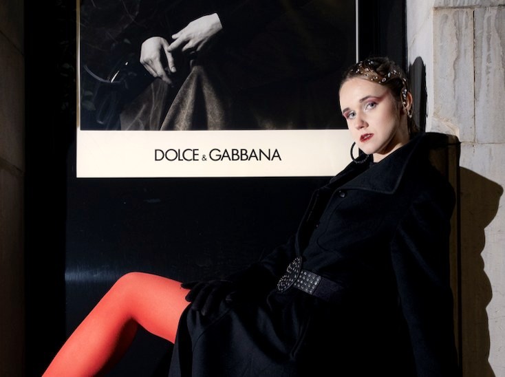 Night editorial in red tights by a Dolce & Gabbana window